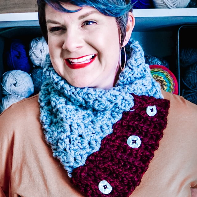 dark haired smiling woman wearing grey and burgundy buttoned cowl