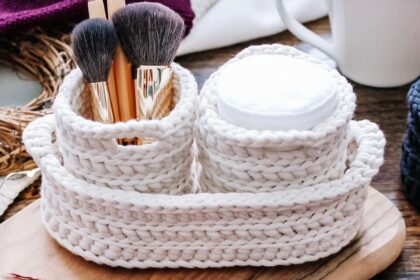 cream crochet nesting pots with two round pots containing cotton pads and makeup brushes, nestled inside a larger oval nesting basket