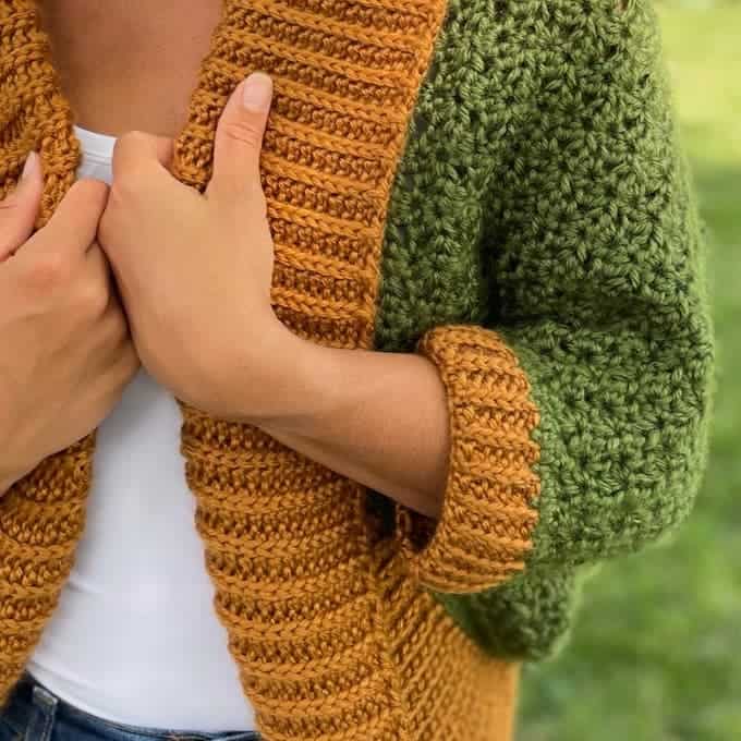 Close up of gold ribbed crochet collar on textured green crochet shrug, styled with white tank top.