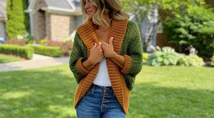 Blond woman wearing green and gold textured crochet shrug with oversized ribbed collar