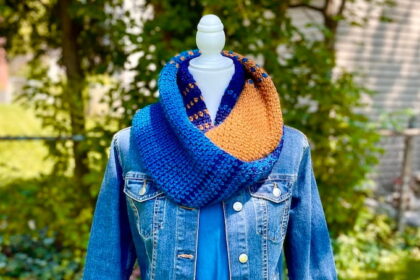 Blue and gold stripy crochet infinity scarf on mannequin, styled with blue denim jacket