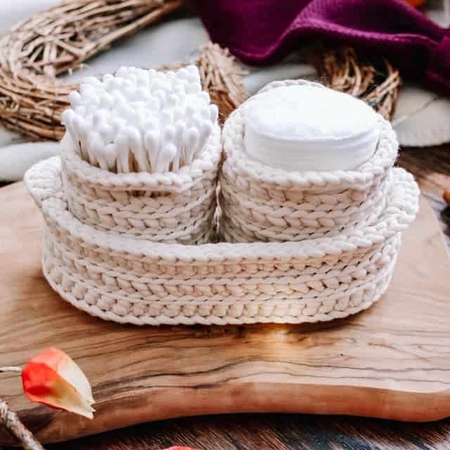 cream crochet nestong baskets, with 2 round small pots inside larger oval trinket tray filled with Qtips and cotton rounds