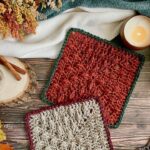 Orange textured crochet leaf blanket square with green border and Fall leaves, with another crochet blanket square in grey and orange placed partially on top