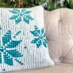 Tunisian Crochet removable cushion cover in cream with blue snowflake motif on cream sofa