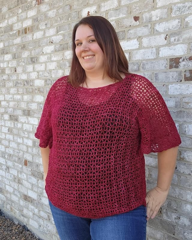 Dark haired woman wearing red lacy crochet top with flowing sleeves