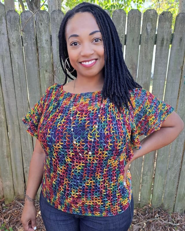 Woman wearing multi colored lacy crochet top with flowing sleeves