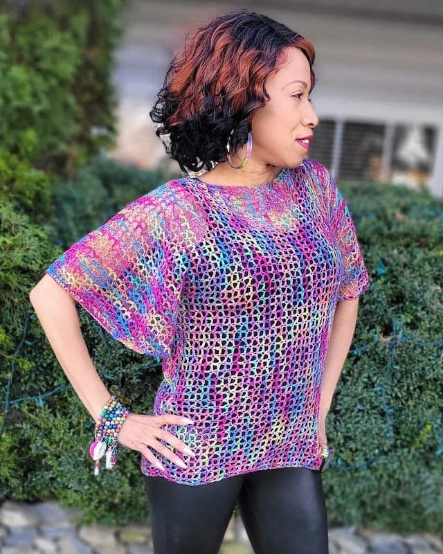 Woman wearing pink multi colored lacy crochet top with flowing sleeves
