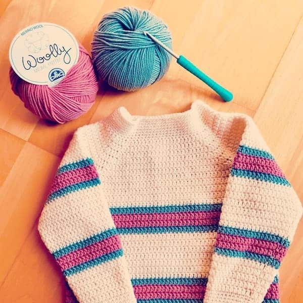 Pink and grey striped cream toddler crochet sweater with 2 balls of yarn and a crochet hook