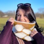 Smiling dark haired woman wearing cream and gold honeycomb Tunisian Crochet Cowl with hexagon design