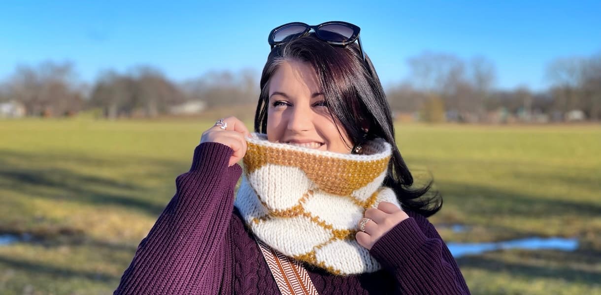 Smiling dark haired woman wearing cream and gold honeycomb Tunisian Crochet Cowl with hexagon design